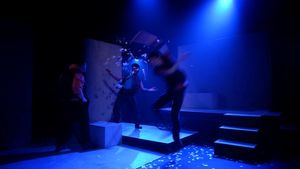 Characters on stage in a blue light. Confetti shoots out around them.